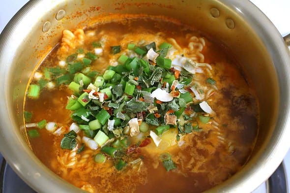 A fiery red spicy ramen pot with green onions, chili oil and ramen noodles